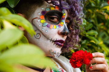 young latin woman with catrina makeup looking at the camera in profile.