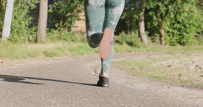 Close up of female legs running on field road outdoors at dawn in summer, concept of healthy running and outdoor exercise. High quality 4k footage