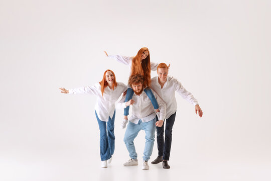 Happy family, redheaded young men, woman and kid wearing casual style clothes spend time together at studio photo shoot.