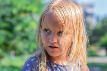close-up portrait of a child, a little girl a beautiful girl, 5 years old blonde, with flowing hair, in a summer park