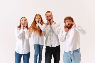 Surprised family, redheaded young men, woman and kid wearing casual style clothes spend time together at studio photo shoot.