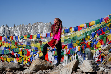 Young female on the top of high mountain in Himalaya with a lot of Buddhist Tibetan flags