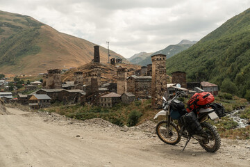 motorcycle loaded with things on long motorcycle journey standing against the backdrop of old stone village in mountains, no people