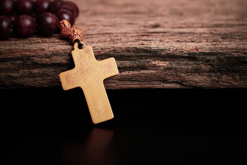 Christian wooden crucifix with Wooden rosary on open bible, Religious concept image,	