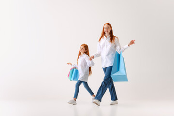 Naklejka premium Beautiful young redhaired woman and little girl going shopping with shopping bags isolated on white background, Concept of black Friday, cyber Monday, sales