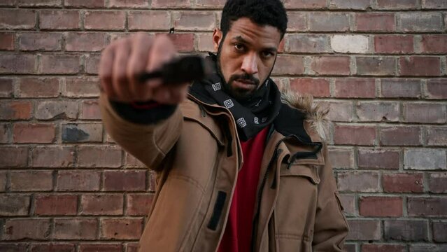 Portrait Of Young Man Pointing Gun At Camera.