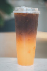 Iced americano black coffee and layer of orange in tall glass