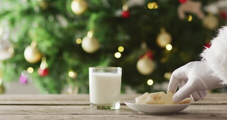 Santa claus dip the biscuit in milk over christmas tree and lights