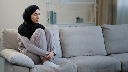 Lonely upset sad muslim young woman sit on sofa health problem interrupted pregnancy divorce...