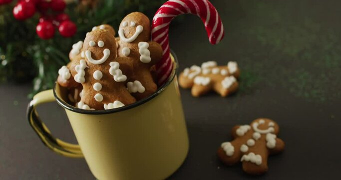 Video of cup with smiling gingerbread men over black background