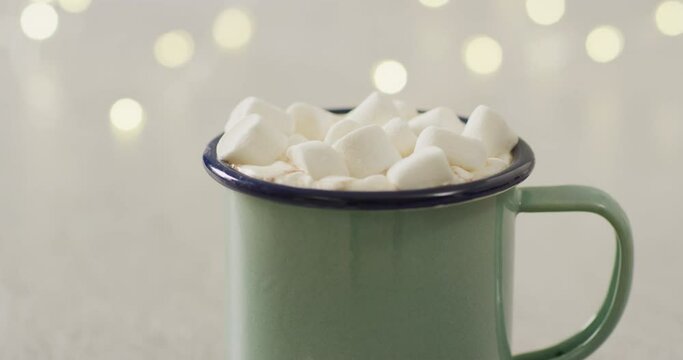 Video of cup of hot chocolate with marshmallows over grey background
