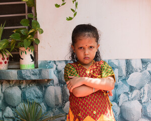 angry Indian young girl in traditional cloth looking at the camera with folded arms or hand.  selective focus on subject and background blur. 