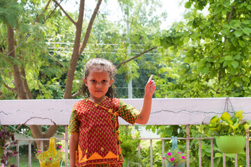 Smiling Indian young girl in traditional cloth showing and pointing with hand and finger to the...