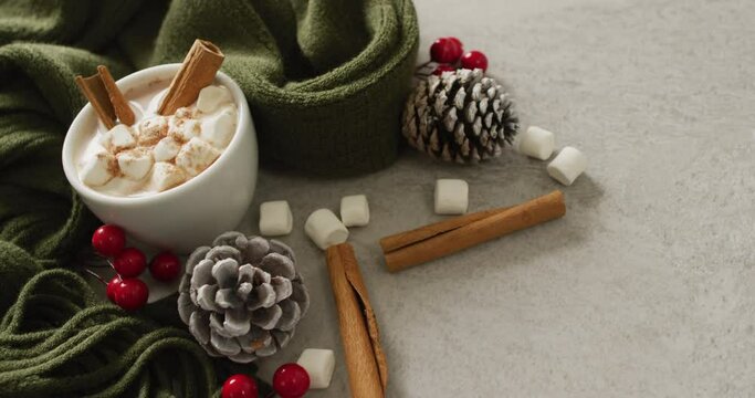 Video of cup of hot chocolate with marshmallows and warm blanket over grey background