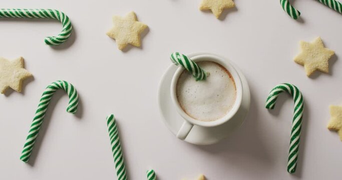 Video of green christmas canes and cup of coffee over white background