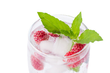 Carbonated drinks with fresh berries and ice. Fresh cold sparkling bubble water with mint, raspberry, black and red currant in transparent glass with ice, angle view macro. Food and drink concept