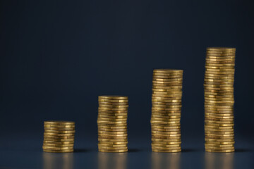 Stacked coins on a dark blue background. Growth investment concept