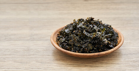 roasted nori seaweed and sesame topping in wood plate on wooden table background. Gim, laver, nori ...
