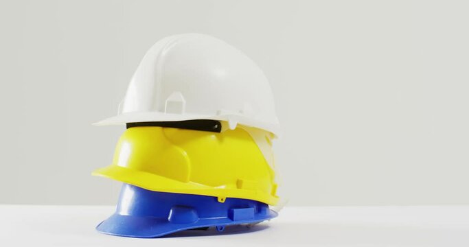 Video of close up of colourful building helmets on white background