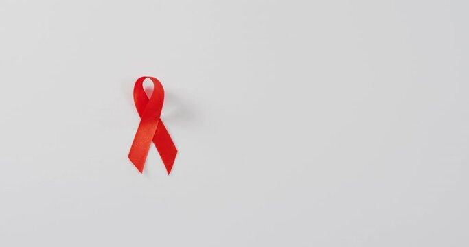 Video of close up of red cancer ribbon on white background
