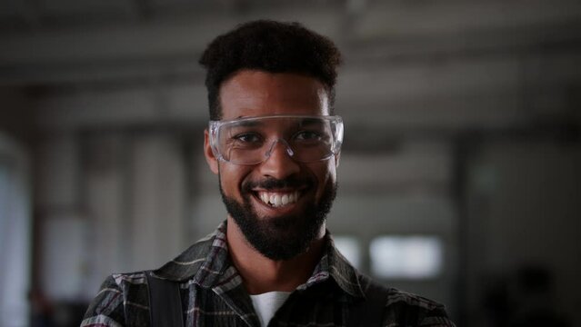 Potrait of young heavy industry worker wearing safety glasses, smiling.
