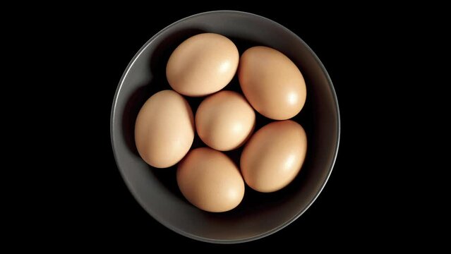 Eggs chicken whole beige in bowl, isolated on black background, rotating, turning, close-up macro, top view.
