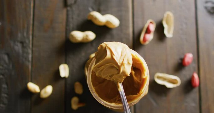 Video of close up of peanut butter and peanuts on wooden background