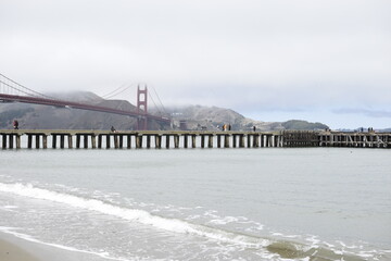 View of a pier in San Francisco with the Golden Gate in the background.