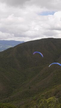 three paraglides fly near a mountain range