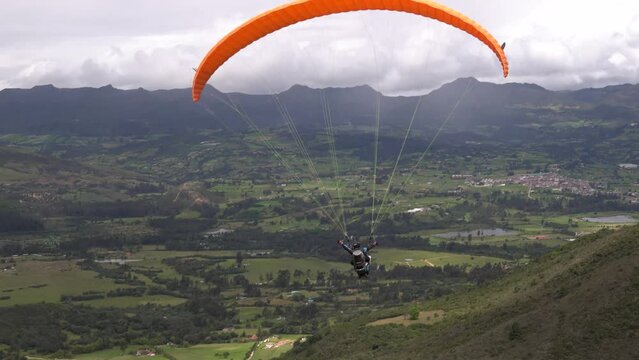 an orange paraglide takes off with two people