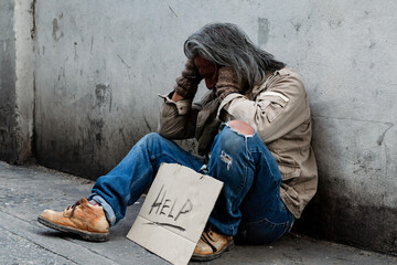 Long-haired old man, Homeless man in a shabby-dressed street, was delighted that he had received money from a yellow purse donor on the floor. waiting for help from others