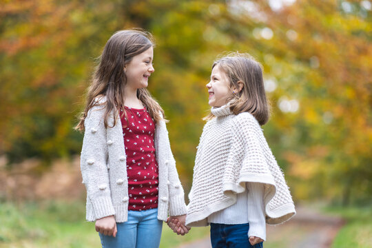 Two lovely girls sisters daughters holding hands in the wood