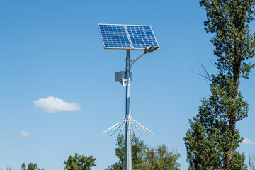Solar device with street lamp on background of blue sky. Street light powered by solar panel with battery included. Alternative energy from the sun