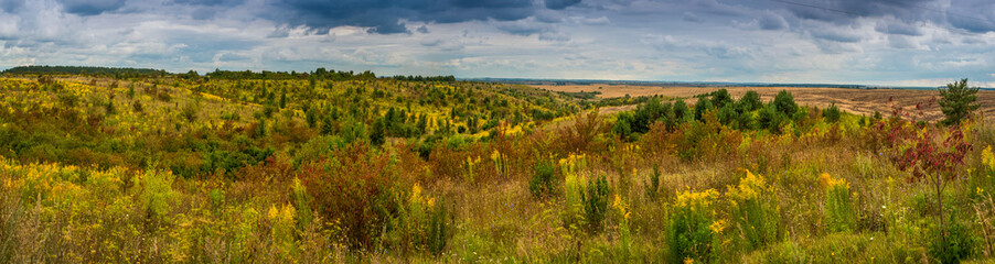 Big panoramic view of autumn landscape under a dramatic cloudy sky. Atmospheric landscape under clouds in rainy weather.