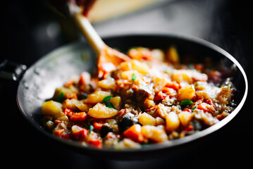 Woman cooking tasty vegetable stew in pan on kitchen
