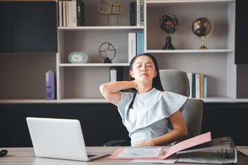 A businesswoman who works in the office looks tired and stressed by pressing her hands