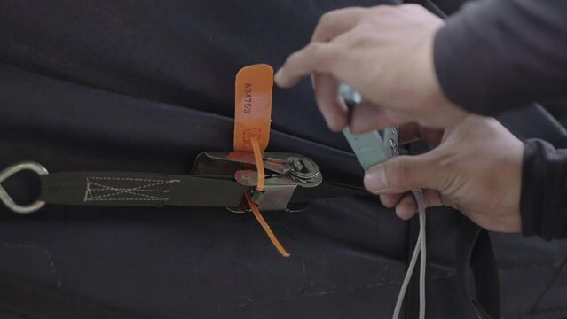 The trunk of the truck is covered with canvas and locked with plastic seal. The truck driver used a digital camera to take a photo of the orange plastic seal for confirm was locked.