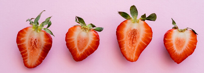 flat lay of red sliced strawberries in row isolated on pink with copy space, banner.
