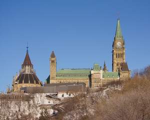 Gothic revival buildings and towers of parliament hill, seen from the park along Ottawa river on a sunny winter day with clear blue sky. Ontario, Canada 