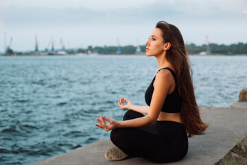 young woman practicing yoga outdoors by the river