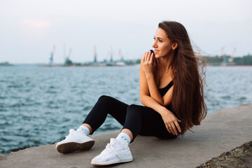 a young woman sits on the embankment, on the banks of the river and looks into the distance