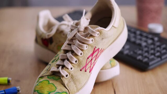 modern concept, updated sneakers with a modern print stand on a table with paints and markers, close-up