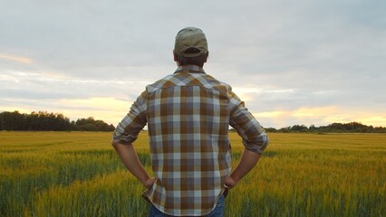 Farmer in front of a sunset agricultural landscape. Man in a countryside field. Country life, food production, farming and country lifestyle.