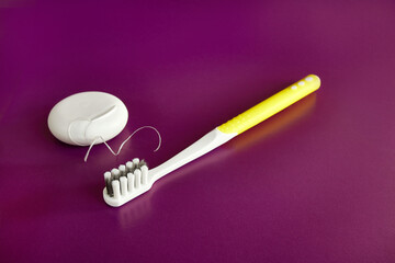 Dental floss and toothbrush on a purple background. Dental care.