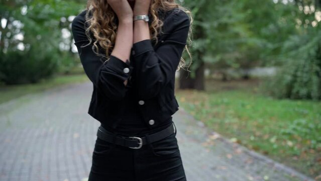 Front view unrecognizable slim young woman touching chest standing in park with panic attack. Nervous Caucasian anxious lady outdoors on alley with symptoms of stress disorder