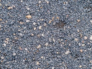 Blue gravel texture background. A lot of small stones in different sizes and colors. The ground is covered with randomly lying objects. Stone material pattern of a footpath or playground.