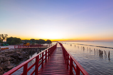 red wooden bridge and sea in the morning,In the morning the red bridge and the sun rise on the horizon. Bridge over the sea in Thailand Thai landscape.