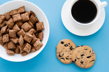top view of cereal puffs in white bowl near cup of coffee and chocolate chip cookies isolated on...