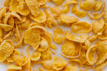 close up view of crispy corn flakes in bowl with organic milk.