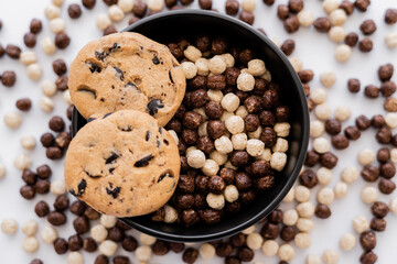 top view of chocolate chip cookies on top of bowl with cereal balls isolated on white.
